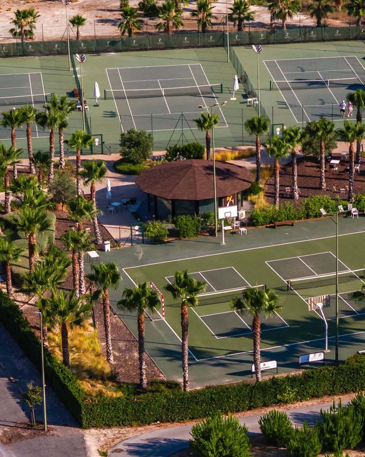 Luftfoto av tennis-, padel- og pickleballbanene på Las Colinas mellom palmer